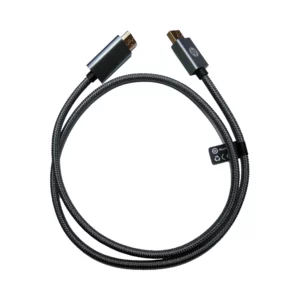 Cable HP DHC-DP03-1M trenzado gris oscuro, vista superior; cable formando un lazo amplio; conectores macho rectangulares en ambos extremos con contactos metálicos dorados y carcasas metálicas grises y fondo blanco. Cable DisplayPort a HDMI.